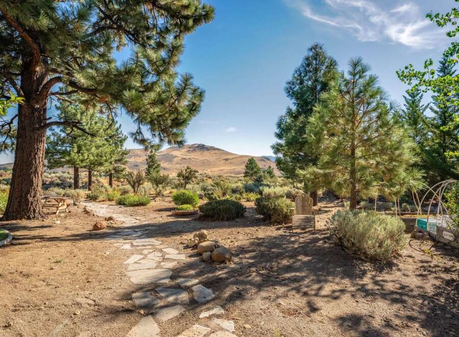 Discover your private oasis with this stunning property featuring a charming stone pathway leading through a mature pine forest.