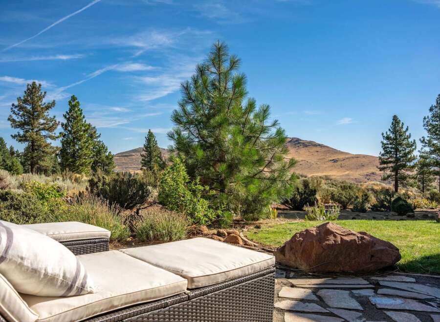 Enjoy breathtaking mountain views from this stunning outdoor living space, complete with comfortable chaise lounges perfect for soaking up the sun.