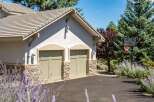 This charming property features a two-car garage with attractive stone accents and light green doors, complemented by a light-colored stucco exterior.