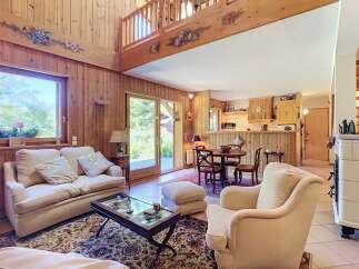 Experience cozy living in this charming wooden cabin-style living room, featuring a plush sofa and armchair perfect for relaxation.