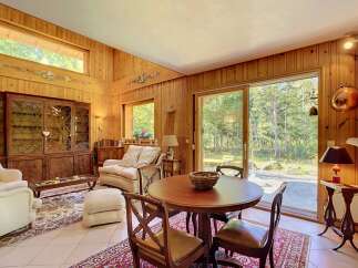 Experience rustic charm in this inviting living and dining area, featuring warm wood paneling throughout and a cozy seating arrangement perfect for relaxation.