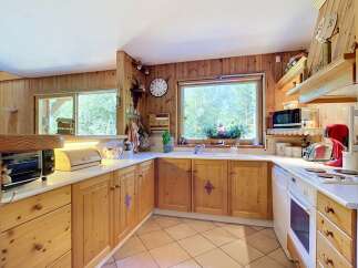 This charming kitchen features warm, knotty pine cabinetry and a spacious countertop perfect for meal preparation.