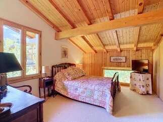 Experience rustic charm in this cozy bedroom featuring a comfortable queen-sized bed adorned with a charming quilt.