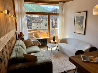 Experience breathtaking mountain views from this charming living room, featuring a cozy green sofa and a stylish white boucle sofa perfect for relaxation.