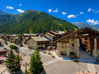 Discover this charming mountain village with its traditional stone buildings and wooden balconies, nestled against a backdrop of lush green forests and majestic peaks.