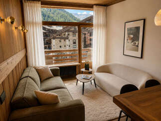 Experience the charm of mountain living in this beautifully appointed living space, featuring a cozy green sofa and a stylish curved cream sofa perfect for relaxation.