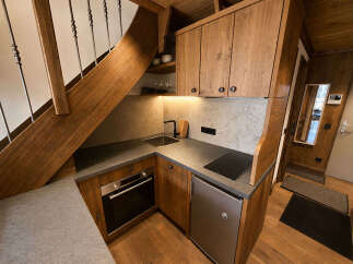 Discover this charming kitchen space, perfectly integrated under a wooden staircase.