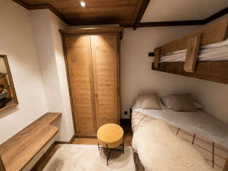 Experience cozy mountain living in this charming bedroom, featuring rustic wooden bunk beds and a comfortable lower bed adorned with plush bedding.