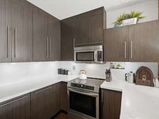 Experience modern living in this sleek kitchen featuring dark wood cabinetry and stainless steel appliances.