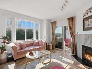 Experience elegant living in this stunning home featuring a plush pink sofa, a cozy fireplace, and a large window offering scenic views.