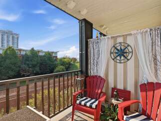 Enjoy your morning coffee or evening relaxation on this charming balcony, complete with two vibrant red Adirondack chairs featuring comfortable striped cushions.