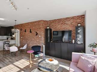 Experience modern urban living in this stylish apartment featuring an exposed brick accent wall and a sleek, contemporary kitchen.