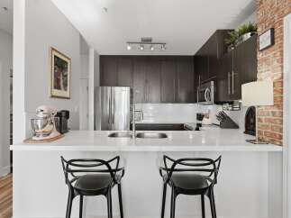 Experience modern living in this stunning kitchen featuring sleek dark wood cabinetry and a gleaming stainless steel refrigerator.