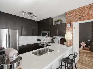 Experience modern living in this stunning kitchen featuring sleek dark wood cabinetry and a pristine white quartz countertop.