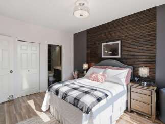 Experience modern comfort in this inviting bedroom, featuring a stylish wood-slat accent wall and a plush upholstered headboard.