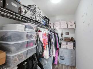 Discover organized living in this spacious walk-in closet, featuring ample shelving and clear storage bins for effortless item visibility.
