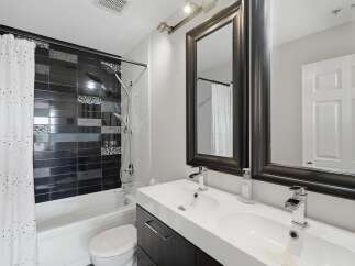 This modern bathroom features a sleek double vanity with chrome faucets and a large framed mirror.