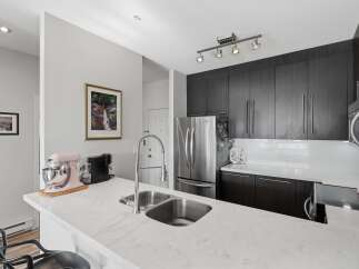 Experience modern living in this stunning kitchen, featuring sleek dark wood cabinetry and a gleaming stainless steel refrigerator.