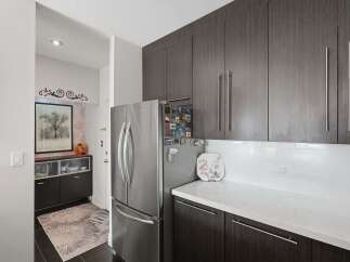 Discover modern living in this stylish kitchen featuring sleek, dark wood cabinetry and a pristine white subway tile backsplash.