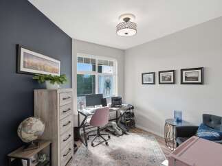 This home office features a dark accent wall adorned with a panoramic cityscape artwork, complemented by a light wood dresser and a vintage globe.