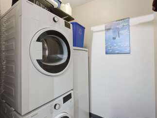 This laundry room features a stacked Blomberg washer and dryer set, perfect for maximizing space in your home.