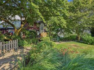 Discover charming curb appeal with this delightful property, featuring a welcoming wooden fence and a lush, mature tree canopy.