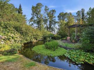 Discover a serene oasis with this beautifully landscaped garden, featuring a tranquil pond surrounded by lush greenery and vibrant hydrangeas.