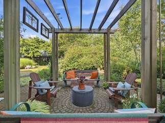 Enjoy outdoor living under this charming wooden pergola, featuring comfortable seating arrangements perfect for relaxation or entertaining.