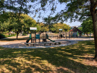 Discover this charming park featuring a vibrant playground with slides, climbing structures, and swings, perfect for family fun.