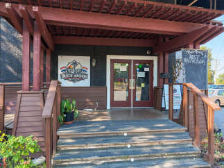 Discover the inviting entrance of Dutch Anchor Restaurant, featuring a charming wooden pergola and a prominent sign.