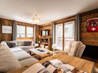 Experience cozy mountain living in this charming living room, featuring rustic wood-paneled walls and a plush sectional sofa perfect for relaxing.