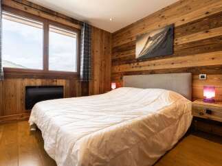 Experience rustic charm in this cozy bedroom, featuring warm wood-paneled walls and a comfortable bed.