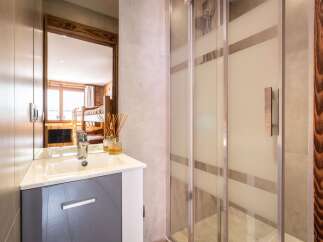 This modern bathroom features a sleek vanity with a white sink and a grey cabinet, complemented by a large mirror reflecting a cozy bunk bed room.