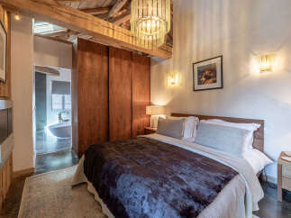 Experience rustic luxury in this charming bedroom featuring exposed wooden beams and a unique chandelier.