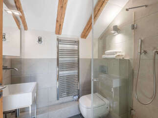 This modern bathroom features a sleek white sink and a wall-mounted chrome towel warmer, perfect for keeping towels cozy.