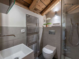 Experience modern comfort in this stylish bathroom, featuring a sleek vessel sink, a chrome heated towel rack, and a convenient wall-mounted toilet.