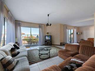 Experience breathtaking lake views from this spacious living room, featuring a large sectional sofa and a cozy seating area perfect for relaxation.