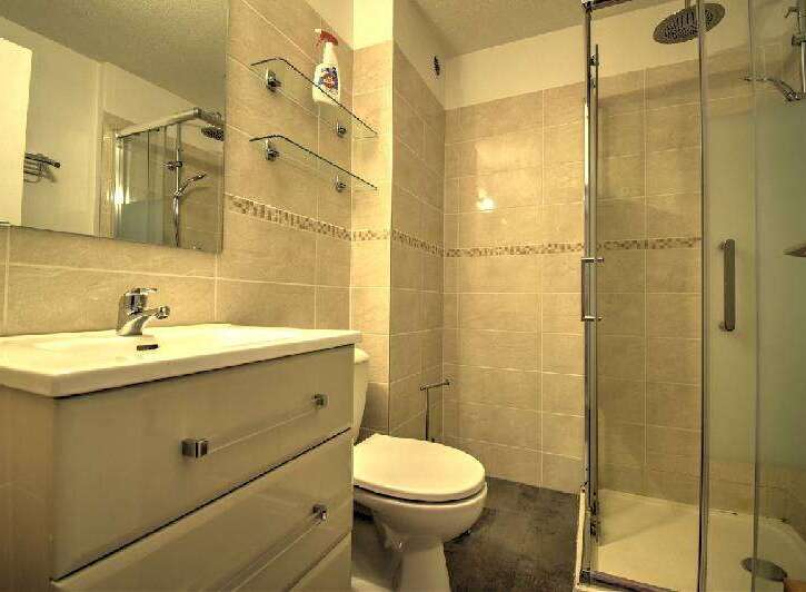 This modern bathroom features a sleek vanity with ample storage, a pristine white toilet, and a spacious glass-enclosed shower.