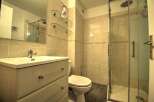 This modern bathroom features a sleek vanity with ample storage, a pristine white toilet, and a spacious glass-enclosed shower.