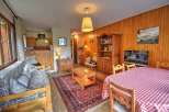Experience cozy living in this charming mountain retreat, featuring a warm wooden interior and a comfortable living area with a plush sofa.