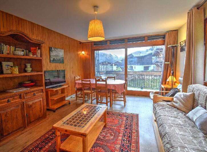 Experience cozy living in this charming apartment, featuring a warm wooden interior and a spacious dining area perfect for family meals.