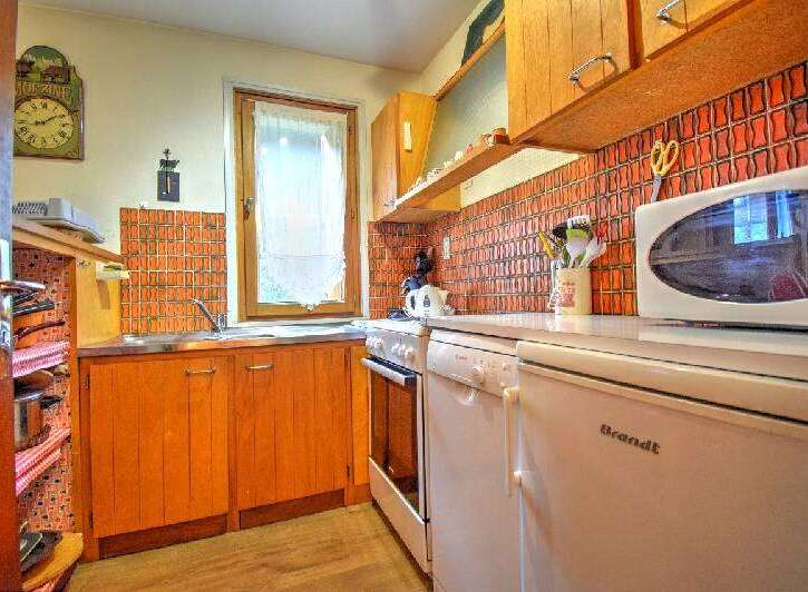 Charming kitchen featuring warm wooden cabinetry and a vibrant orange tiled backsplash.