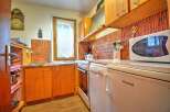 Charming kitchen featuring warm wooden cabinetry and a vibrant orange tiled backsplash.