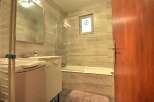 This modern bathroom features a sleek vanity with a built-in sink and ample storage, complemented by a spacious bathtub and a convenient washing machine.