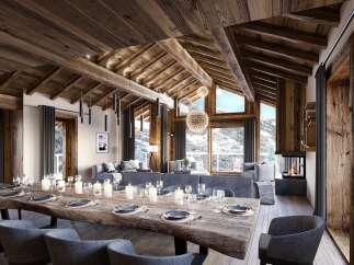 Experience luxury mountain living in this stunning chalet, featuring a grand dining area with a rustic wooden table set for a feast.