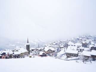 Experience the charm of a winter wonderland with this picturesque village nestled in the snow-covered mountains.