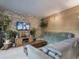 Experience cozy living in this charming mountain-inspired living room, featuring a striking stone accent wall and warm wooden paneling.