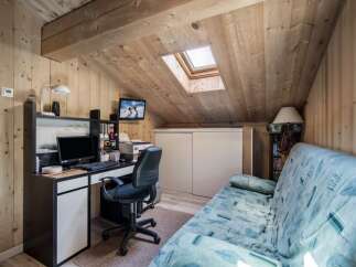 This charming attic room features a cozy workspace with a desk, computer, and printer, perfect for remote work or study.