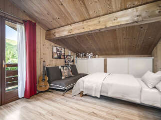 Experience cozy mountain living in this charming attic bedroom, featuring a convertible sofa and a comfortable bed, perfect for maximizing space.