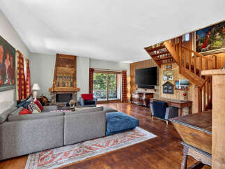 Experience rustic charm in this inviting living room, featuring a grand stone fireplace and warm wooden accents throughout.